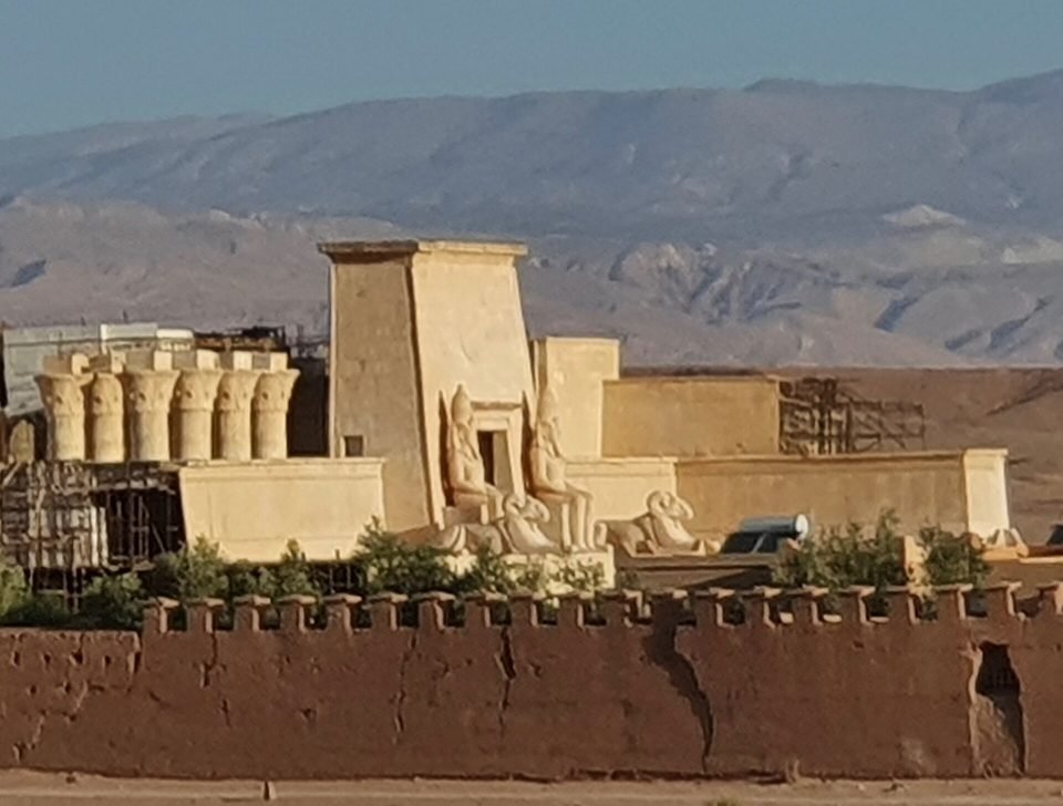 An Egyptian temple film set with columns and statues behind a crenellated wall at Atlas Studios, mountains behind