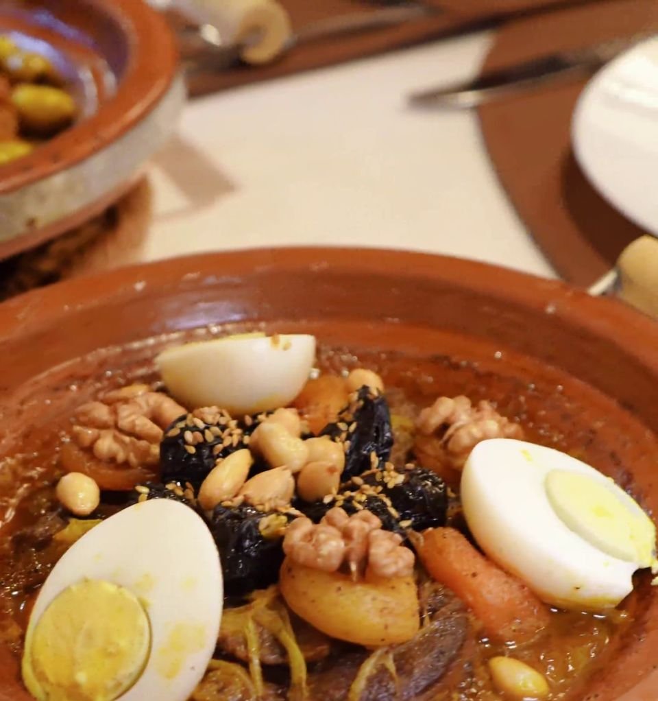 Close up of a tagine with hard boiled eggs, prunes, walnuts and almonds in a clay dish